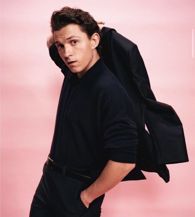 Tom Holland segurando uma blusa com um fundo rosa