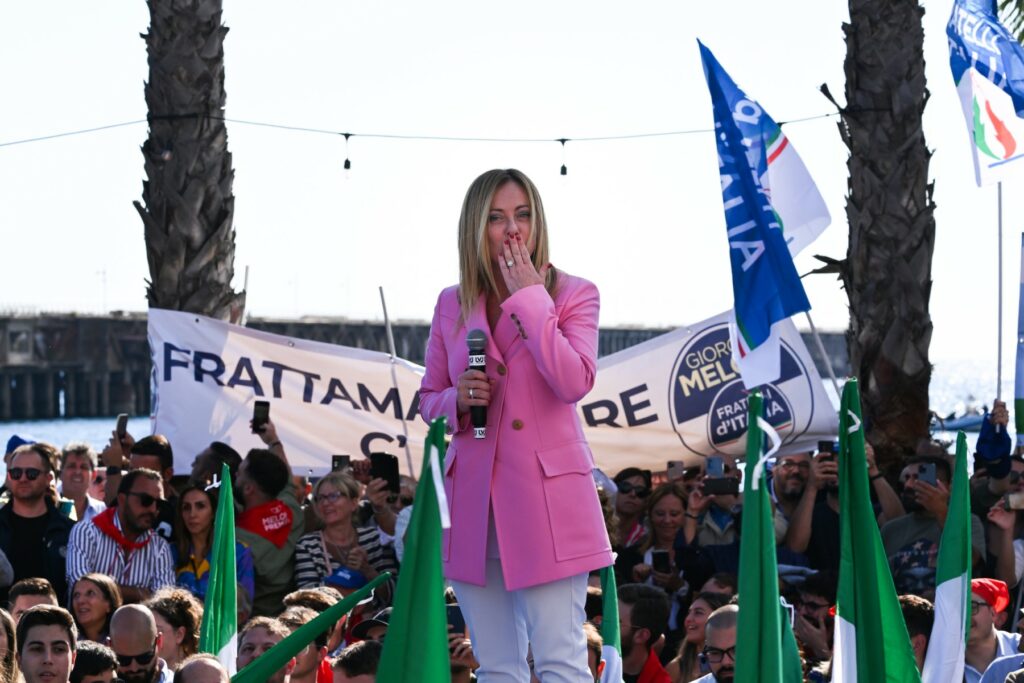 Foto de Giogia Meloni mandando um beijo durante um discurso numa manifestação